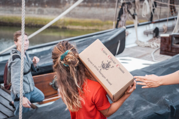 France, Bretagne, 2025-07. In Douarnenez, several volunteers load a ton of cargo consisting of wine, cider, and stills aboard the Grayhound, a replica of a 1776 customs ship. Photographs by Jonathan Cathala / Collectif DR. France, Bretagne, 2025-08. A Douarnenez, plusieurs bénévoles chargent une tonne de cargaison de vin, cidre et alambic à bord du Grayhound, réplique d'un navire douanier de 1776.  Photographies de Jonathan Cathala / Collectif DR.