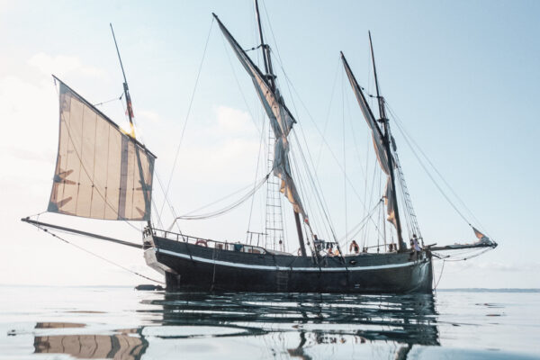 France, Bretagne, 2025-08. The Grayhound sailing ship, a replica of a 1776 boat, transports sea cargo in Brittany. Photographs by Jonathan Cathala / Collectif DR. France, Bretagne, 2025-08. La réplique du voilier Grayhound de 1776 transporte du fret maritime en Bretagne. Photographies de Jonathan Cathala / Collectif DR.